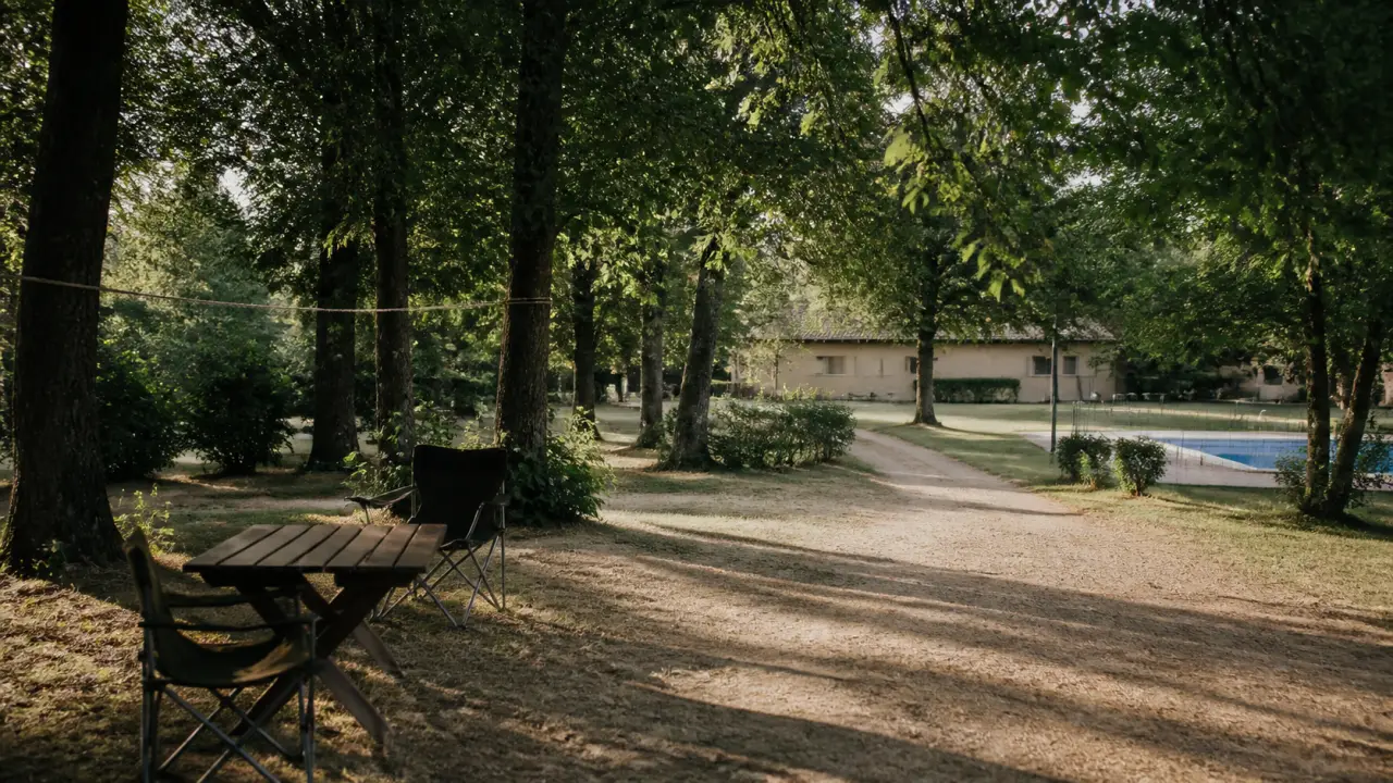 Camping rignac aveyron : emplacements ombragés, table et chemin vers la piscine