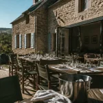 Gîte aveyron 30 personnes : grande salle avec tables et terrasse